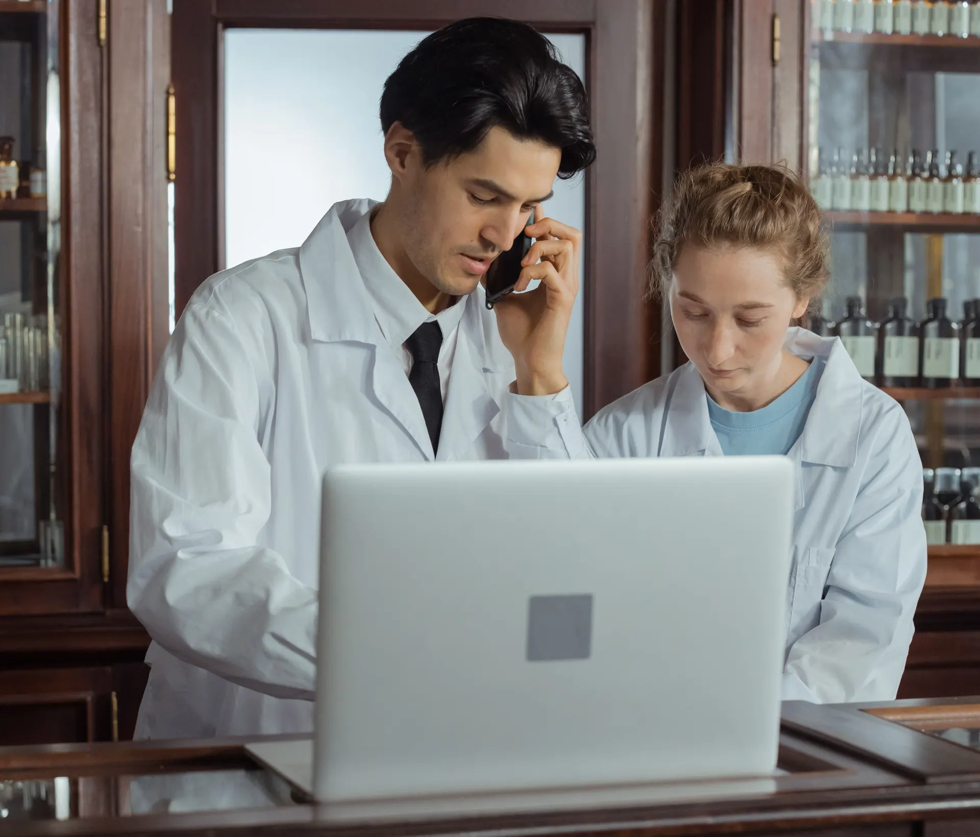 Dois farmacêuticos atendendo no balcão, um deles ao telefone